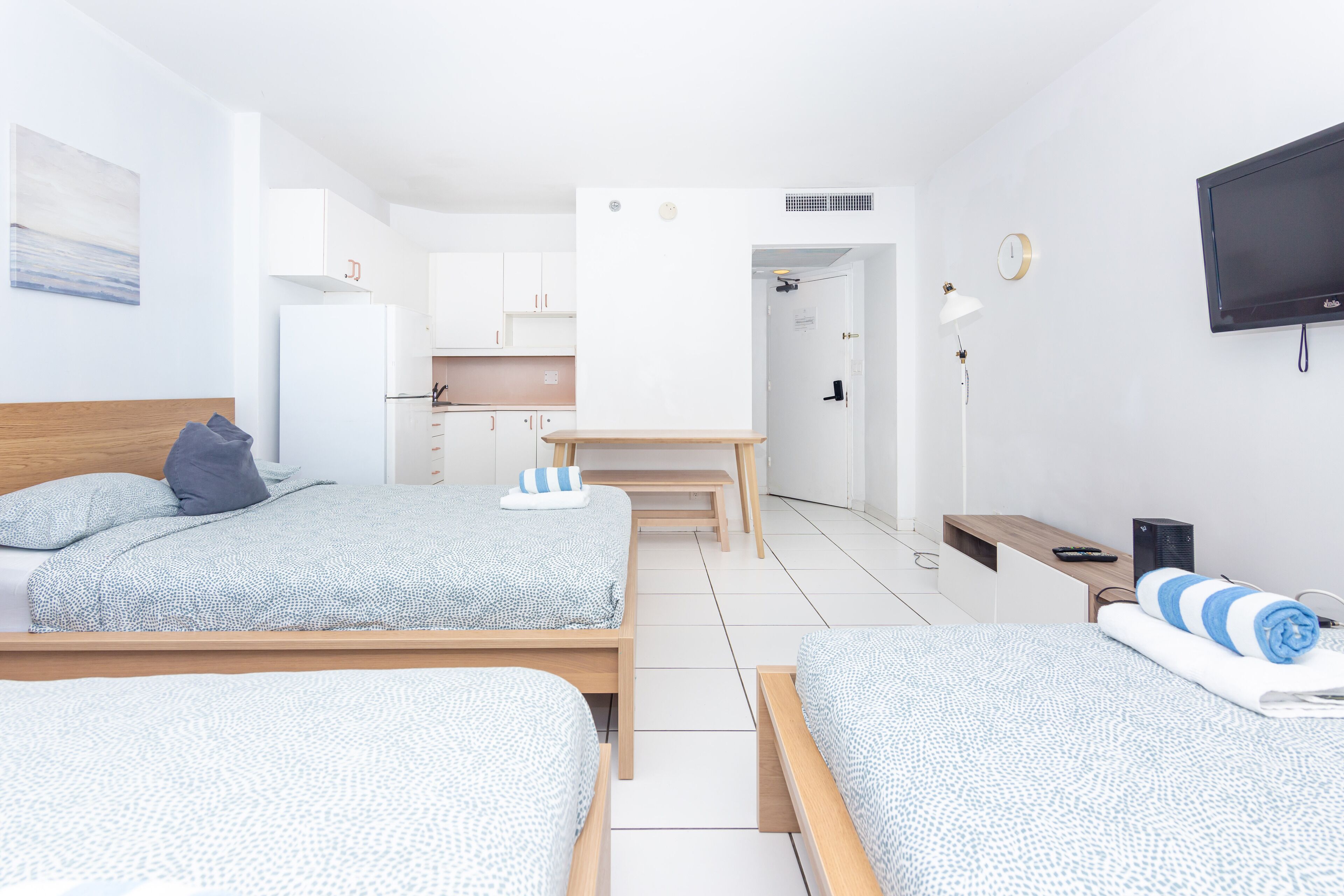 Une chambre d’hôtel moderne équipée de deux lits, d’un bureau, d’une télévision et d’une kitchenette.