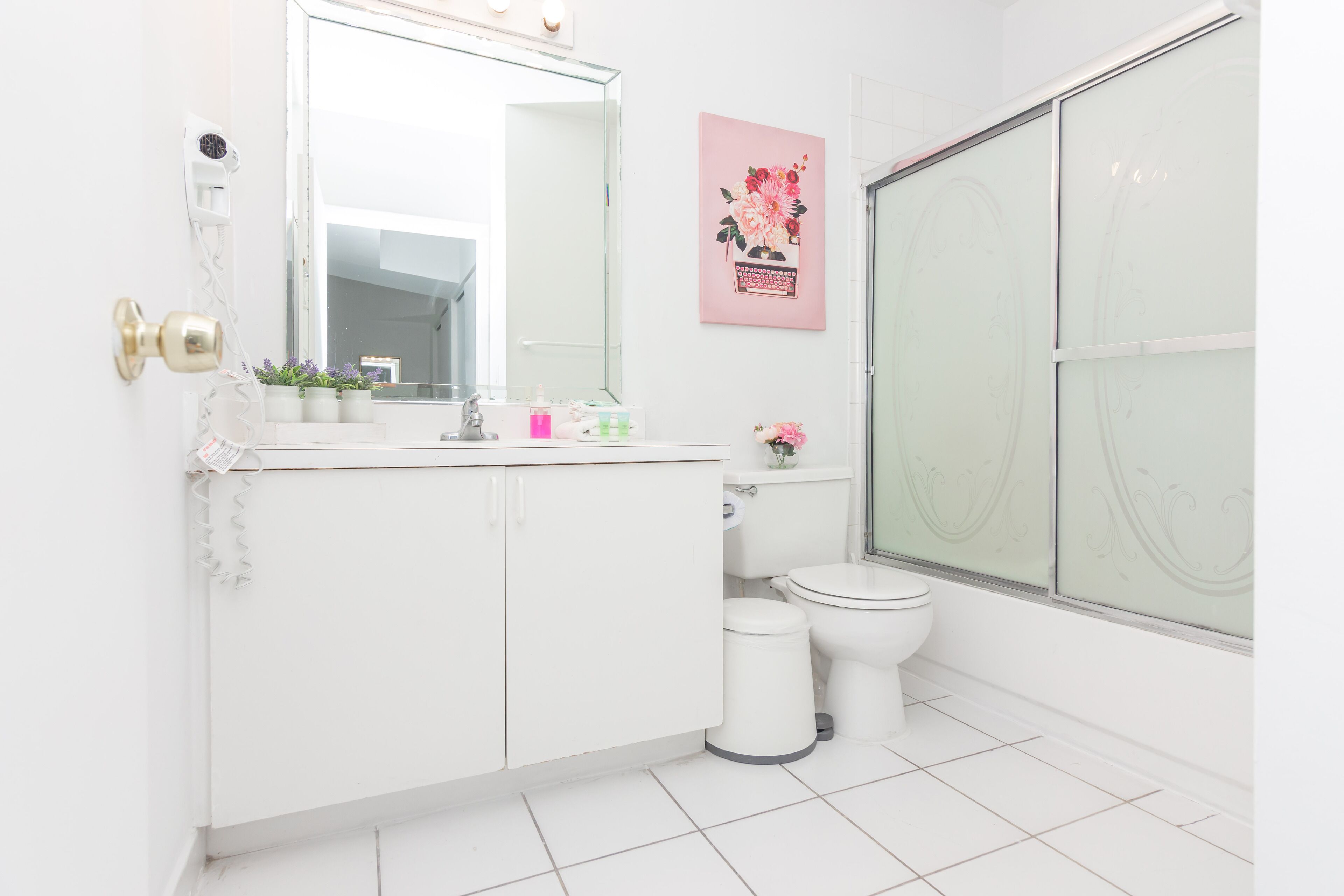 Ein modernes Badezimmer mit einem weißen Waschtisch, einem großen Spiegel, einer Toilette und einer Duschkabine.