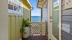 A wooden deck with a view of the ocean, a potted plant, and a door with a nameplate.