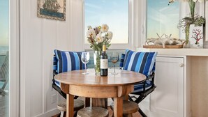 A dining area with a round wooden table, blue-striped chairs, and a vase of flowers.