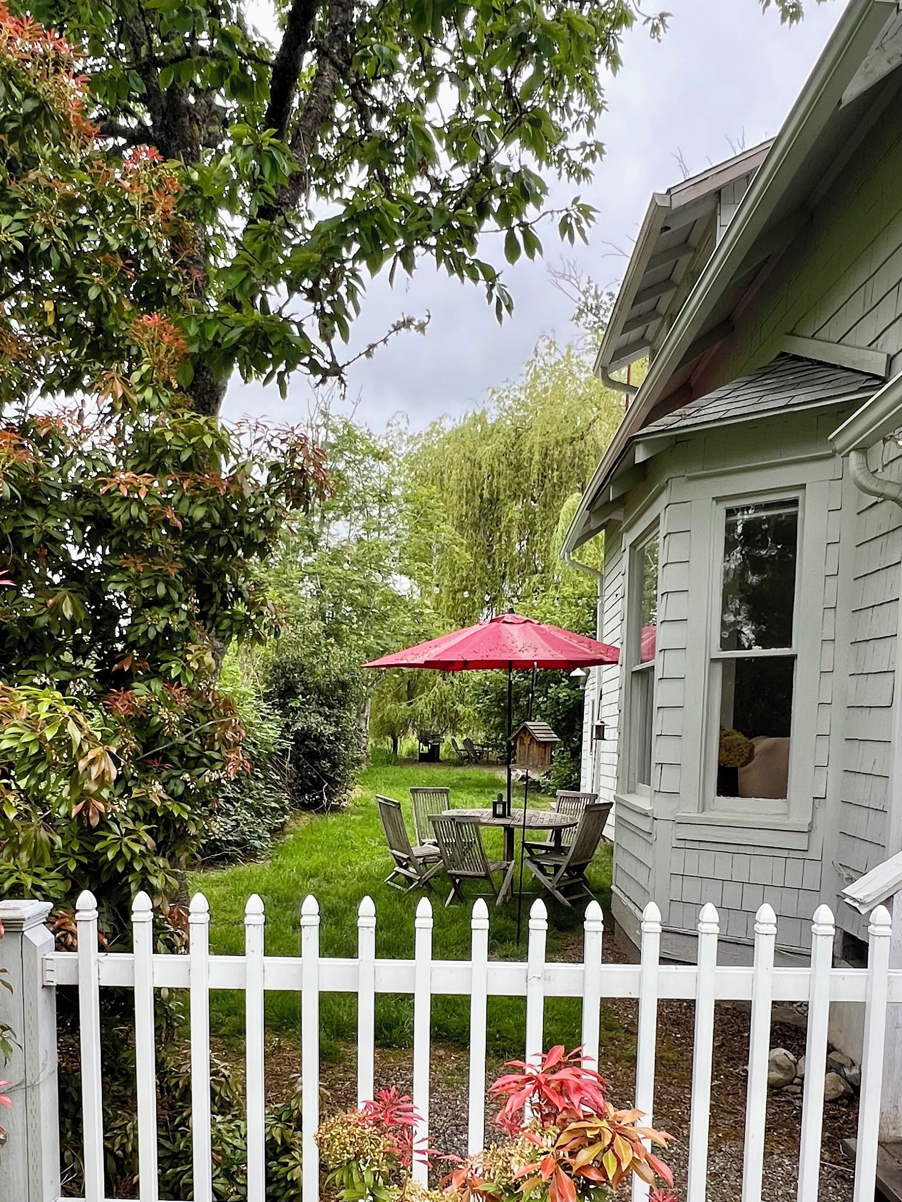 En boligejendom med en indhegnet have, en terrasse med havemøbler og et hus med et vindue.
