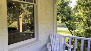 A covered porch with a white chair and a trash bin. - Vashon Farmhouse  (Vashon)