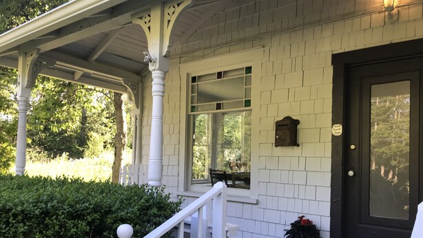 A white porch with a dark door, white columns, and a small mailbox. - Vashon Farmhouse  (Vashon)