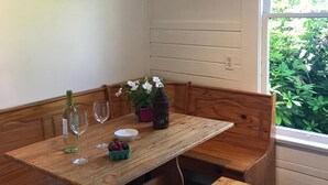 A wooden bench with a table, a bottle of wine, two wine glasses, a bowl, and a potted plant with white flowers. - Vashon Farmhouse  (Vashon)