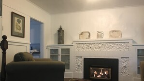 A living room with a fireplace, a sofa, and a cabinet with glass doors. - Vashon Farmhouse  (Vashon)
