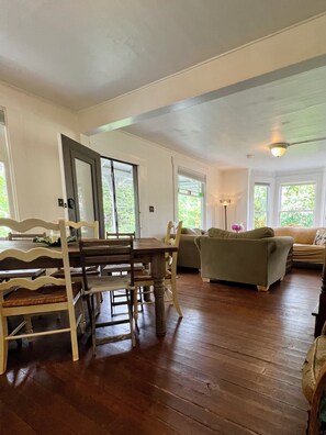 Un vaste espace de vie comprenant une table et des chaises en bois, un canapé et une lampe.
