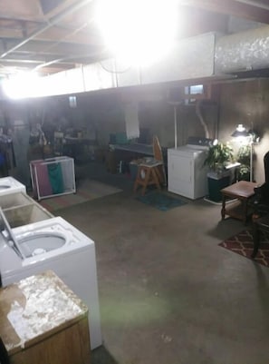Laundry room with a washing machine and dryer, a stool, and a table with a lamp.