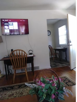 Relax in this inviting living space with a flat-screen TV, dining table, and comfortable chair.