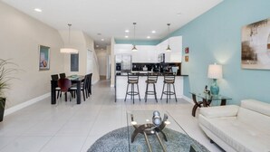 Una sala de estar moderna con comedor, cocina y barra.