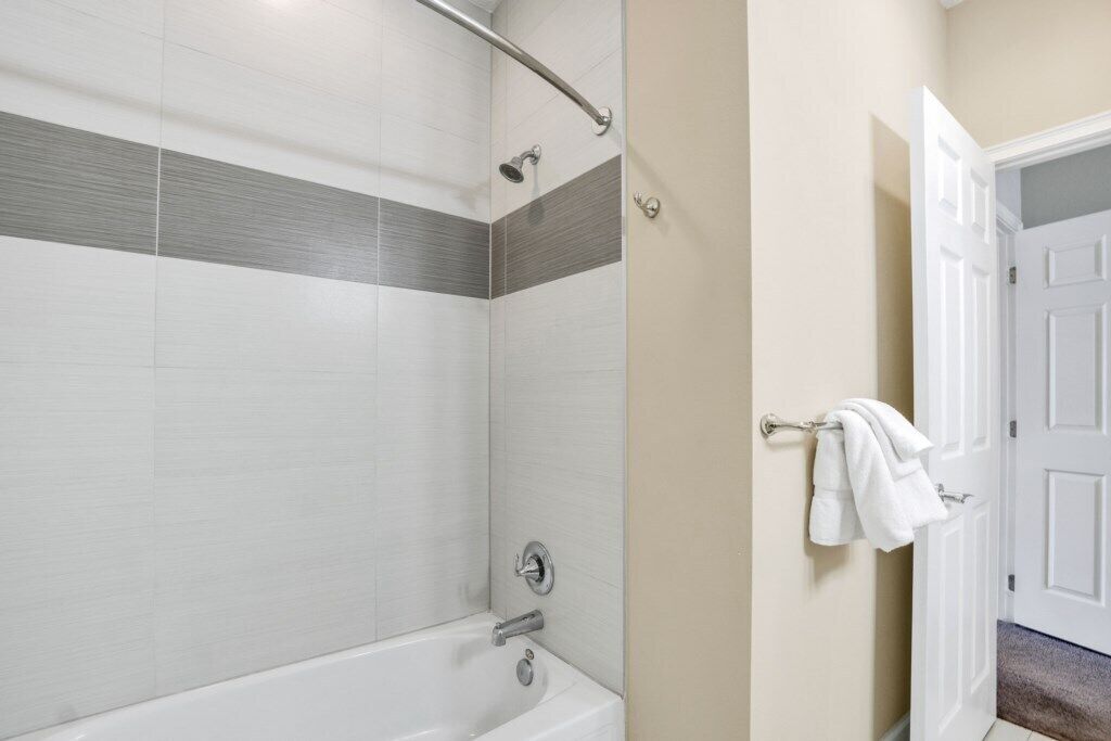 A modern bathroom with a bathtub, shower, and towel rack.