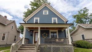 A two-story house with a front porch, a wooden staircase, and a decorative wreath.