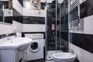 Ein modernes Badezimmer mit Waschmaschine, Waschbecken und Duschkabine.
