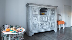 Quarto com um armário branco, uma mesa com café da manhã e uma cadeira.