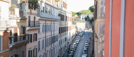 A narrow street lined with multi-story buildings, each with balconies and shutters.