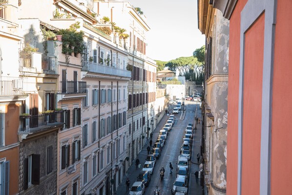 A narrow street lined with multi-story buildings, each with balconies and shutters. - MAISON Spanish steps (Roma)