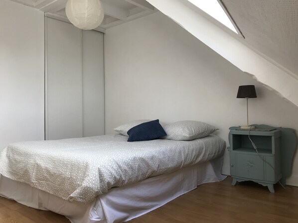 A bedroom with a bed, pillows, a nightstand, a lamp, and a ceiling light. - 60 m2 Près du Port, Ville Close et Plages (Concarneau)