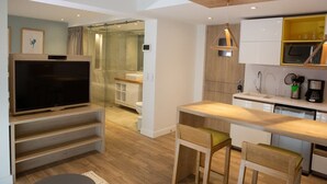 Eine moderne Küche mit integriertem Fernseher, einer Holzauslage und einer Duschkabine aus Glas.