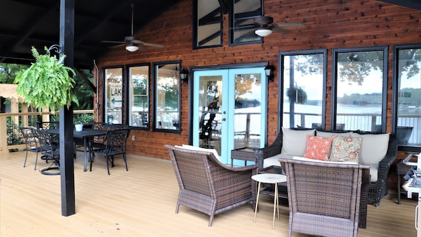 A covered outdoor area with wicker furniture, a table, and chairs. - Old Lake Charm with Million Dollar Views (Troutman)