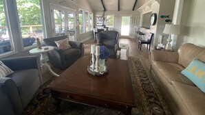 A spacious living room with a large window, a ceiling fan, and a dining area with bar stools. - Old Lake Charm with Million Dollar Views (Troutman)