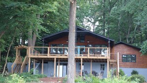 A two-story wooden cabin with a balcony, surrounded by dense forest. - Old Lake Charm with Million Dollar Views (Troutman)
