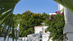 A modern building with a white facade, surrounded by lush greenery and flowering plants.