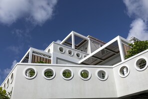 A modern building with multiple levels, circular windows, and a sloped roof.