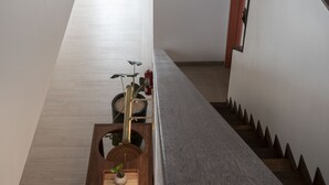 A modern interior with a wooden staircase, a small wooden table with a plant, and a fire extinguisher.