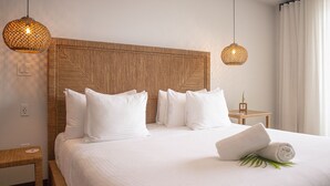 A neatly made bed with white linens and pillows, a woven headboard, and two hanging wicker lamps.