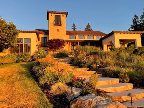 A multi-story building with a tower, stone facade, and a landscaped garden with steps leading to the entrance.