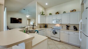 A modern kitchen with white cabinetry, a built-in oven, microwave, and refrigerator. - 2621 SW 27th St. Cape Coral (Cape Coral)
