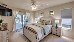 A bedroom with a bed, a nightstand, a ceiling fan, and a view of the outdoors. - 2621 SW 27th St. Cape Coral (Cape Coral)