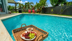 Una piscina amb una cistella de vimet que conté un plat de raïm i un plat de galetes.