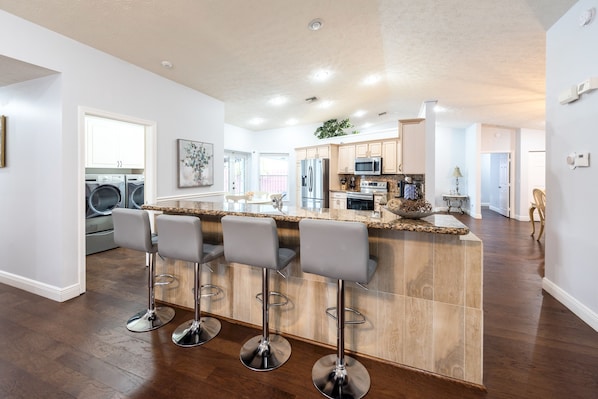 Una cocina moderna con una isla central, taburetes de bar y lavadora y secadora integradas.