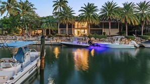 A marina with boats docked, palm trees, and a building with large windows. - Waterfront paradise in Key Largo with resort style amenities (Key Largo)