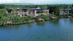 A waterfront resort with multiple buildings surrounded by lush greenery and palm trees. - Waterfront paradise in Key Largo with resort style amenities (Key Largo)