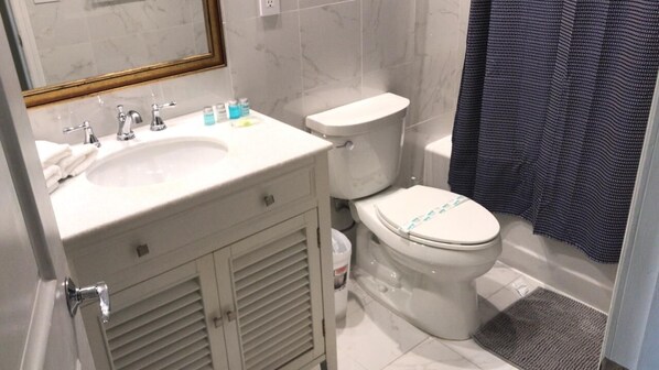 A bathroom with a white sink, two faucets, a toilet, and a shower curtain.