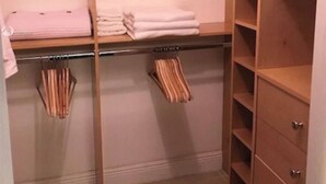 Un dressing avec des étagères en bois, une tringle à vêtements et un porte-manteau en métal.