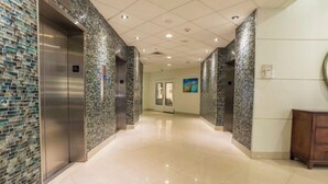 Un couloir moderne doté d’ascenseurs, d’un sol poli et d’un mur orné d’une mosaïque.