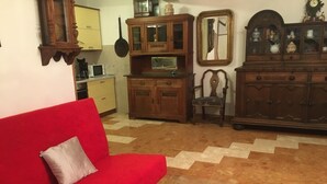 Un salon avec un canapé rouge, des meubles en bois et un sol carrelé.
