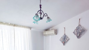 Un dormitorio con cama, mesita de noche, candelabro, aire acondicionado y adornos en la pared.