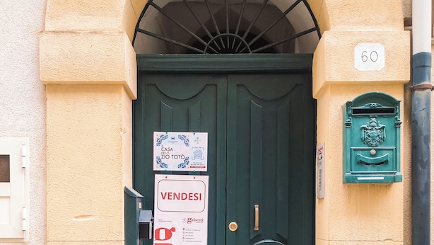 Una puerta doble verde con un letrero que dice 'VENDESI' y un buzón.