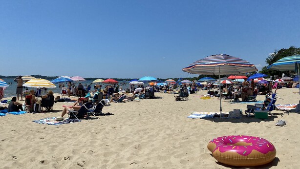 A crowded beach with numerous colorful umbrellas and beachgoers. - Fern Cottage Crystal Beach (Fort Erie)