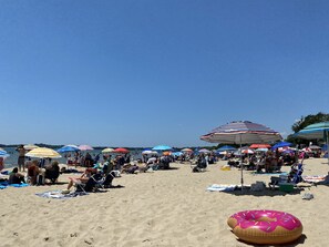 Une plage bondée, avec de nombreux parasols colorés et de nombreux vacanciers.