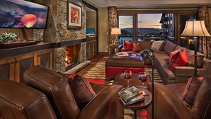 A cozy living room with leather furniture, a fireplace, a television, and a view of the city.