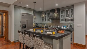 Una cocina moderna con gabinetes grises, electrodomésticos de acero inoxidable y una isla central con asientos.