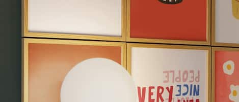 A wall with framed artwork, including a face, a popcorn bucket, and a light fixture.