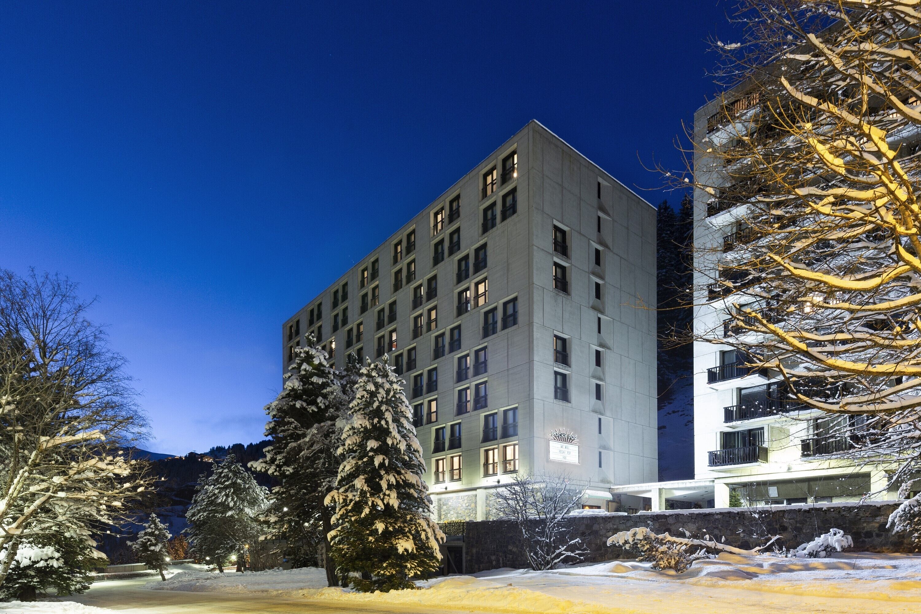 A multi-story building with a modern architectural design, featuring a symmetrical facade and numerous windows.