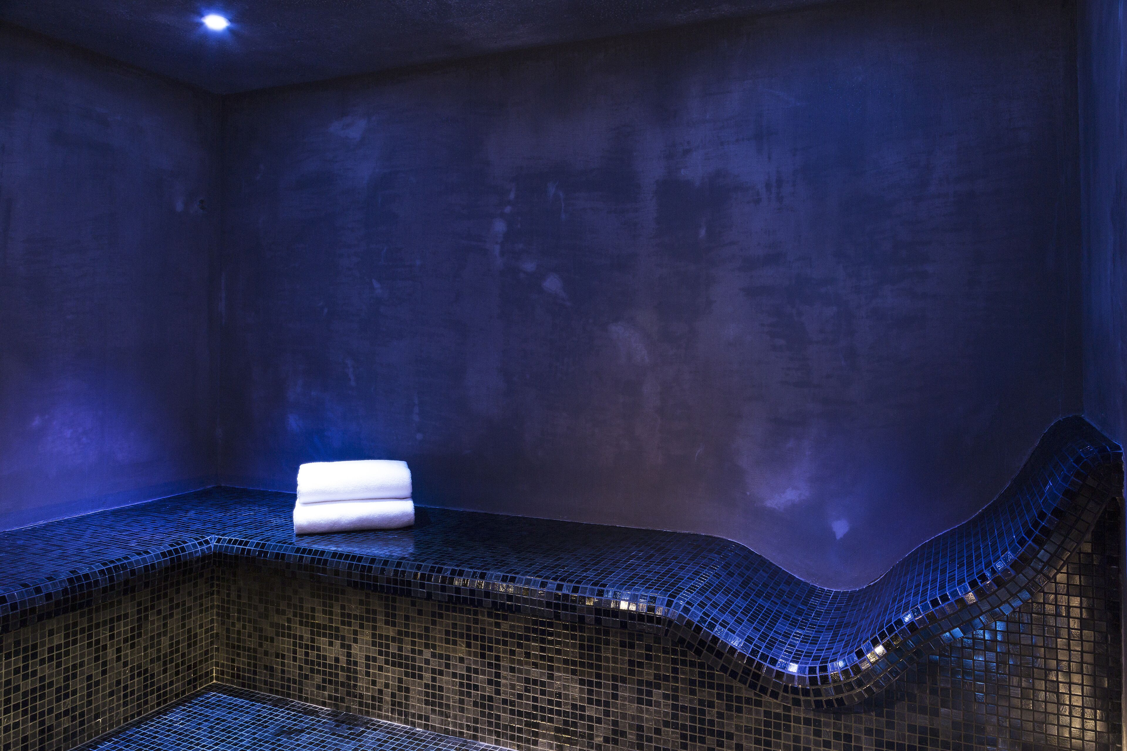 Ein Wellnessraum mit gefliestem Boden und einer gebogenen Sitzbank.