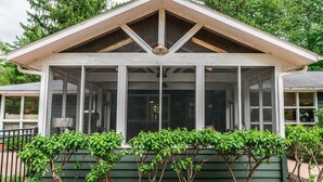 Uma casa com varanda coberta e fachada verde.