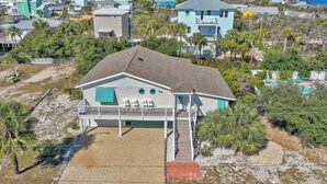 A coastal house with a balcony, surrounded by palm trees and a sandy beach. - Cape Haus Extra (Port St. Joe)
